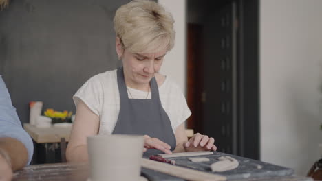 three elderly people work on a potter's wheel in slow motion