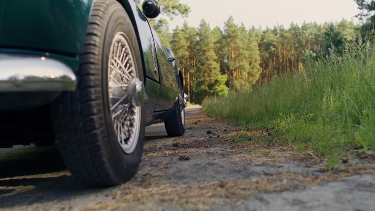 Classic car on a road surrounded by trees