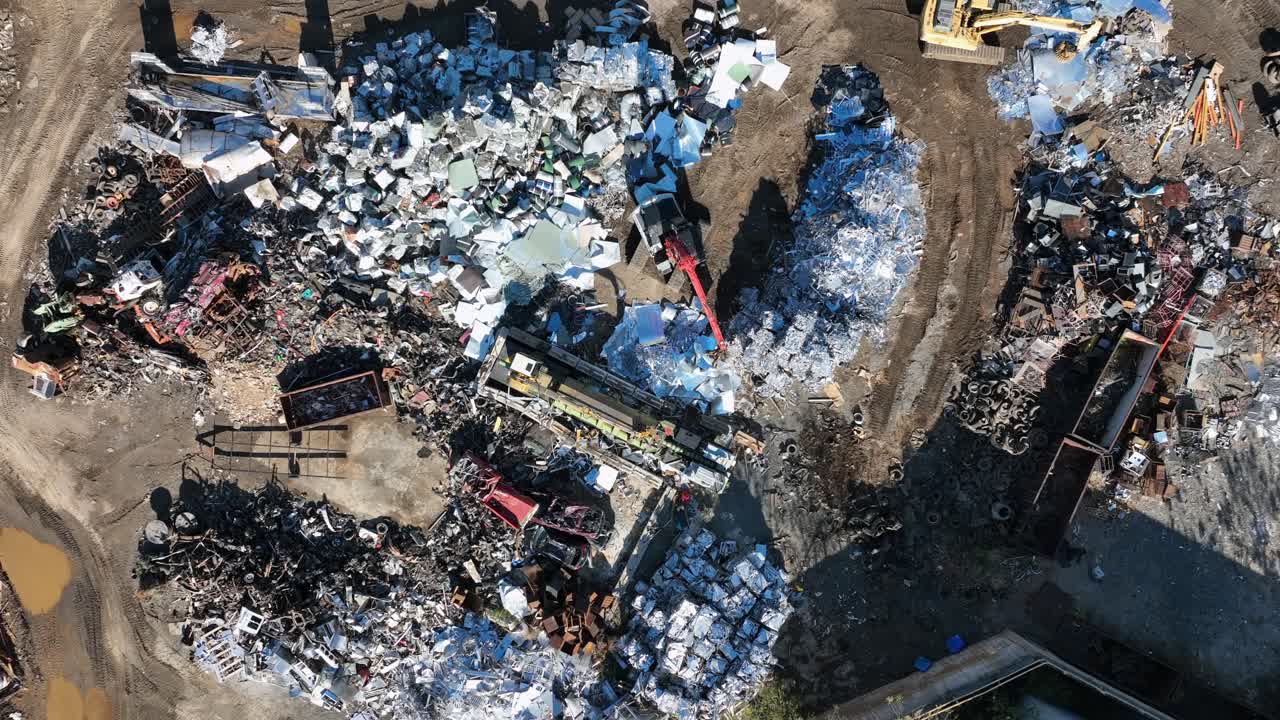 Aerial top down of working excavator on scrapyard. Sunny day in american industrial area. Transport of metal