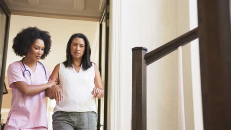 helping woman walk down stairs, caregiver providing support in home setting