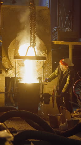 trabajadores de fundición industrial vierte metal fundido con llamas intensas y humo