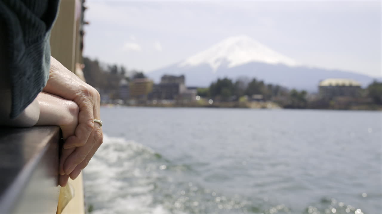 People holding hands while enjoying a peaceful moment on a boat while admiring the stunning view of a snow-covered Fuji mountain in Japan. Kawaguchiko Lake
