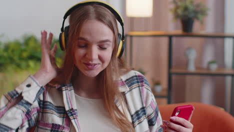 Una-Joven-Bastante-Caucásica-Con-Auriculares-Escuchando-Música-Bailando,-Cantando-En-El-Salón-De-Casa