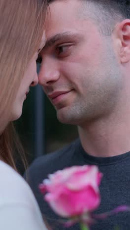 a guy in a black tshirt is looking at a girl holding a pink rose a guy in a black tshirt is looking at a girl holding a pink rose date