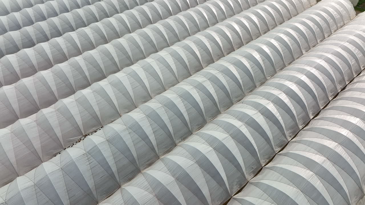 Pattern of greenhouse white plastic to warm plants in cold growing winter season. Aerial of horticulture.