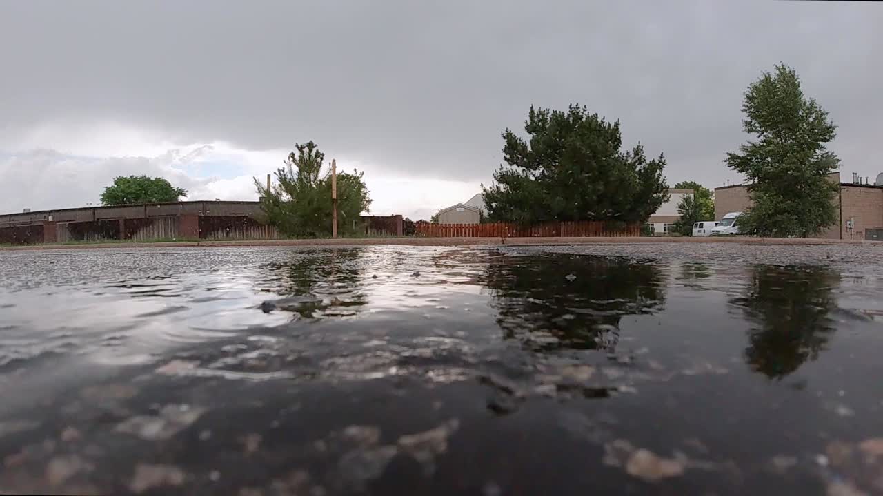 Raindrops hitting a puddle in an asphalt driveway in slow motion
