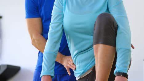 trainer assisting senior woman in performing yoga 4k