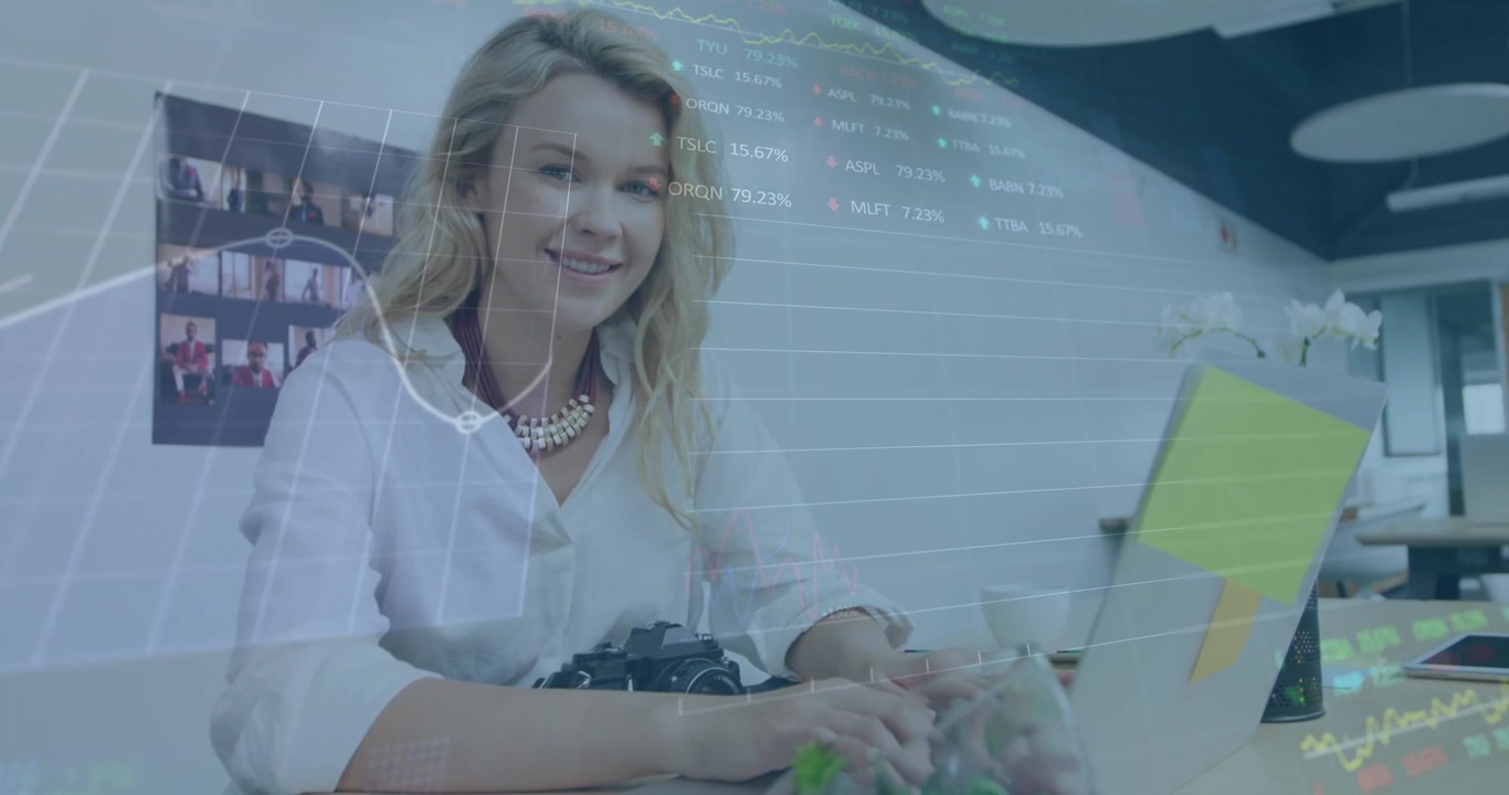 A young female business creative is working in a modern office, using a laptop computer and smiling
