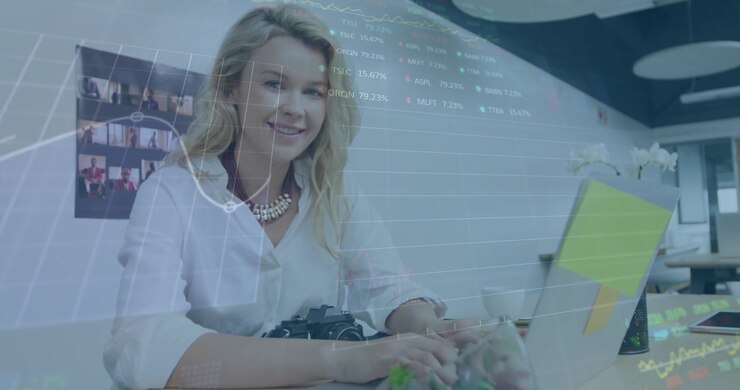 A young female business creative is working in a modern office, using a laptop computer and smiling