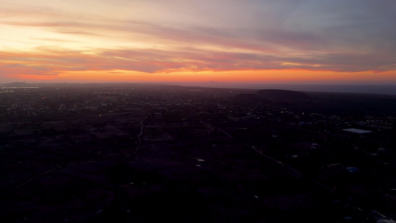 dramática puesta de sol sobre un paisaje costero con el cielo volviéndose de color naranja profundo como las olas ruedan suavemente a lo largo de la costa