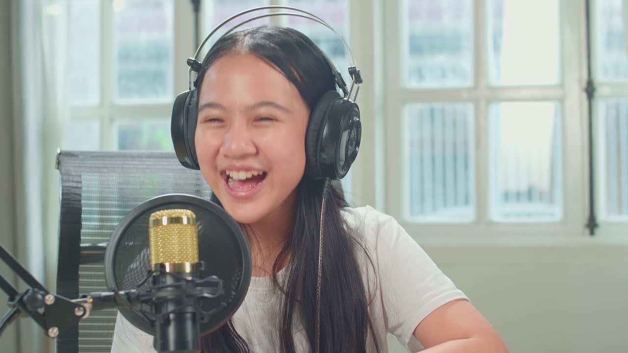 Over Shoulder View Of Asian Boy Host Record Podcast Use Microphone Wear Headphone Interview Happy Kid Girl Guest Conversation For Content In His Home Studio. Content Creator Concept