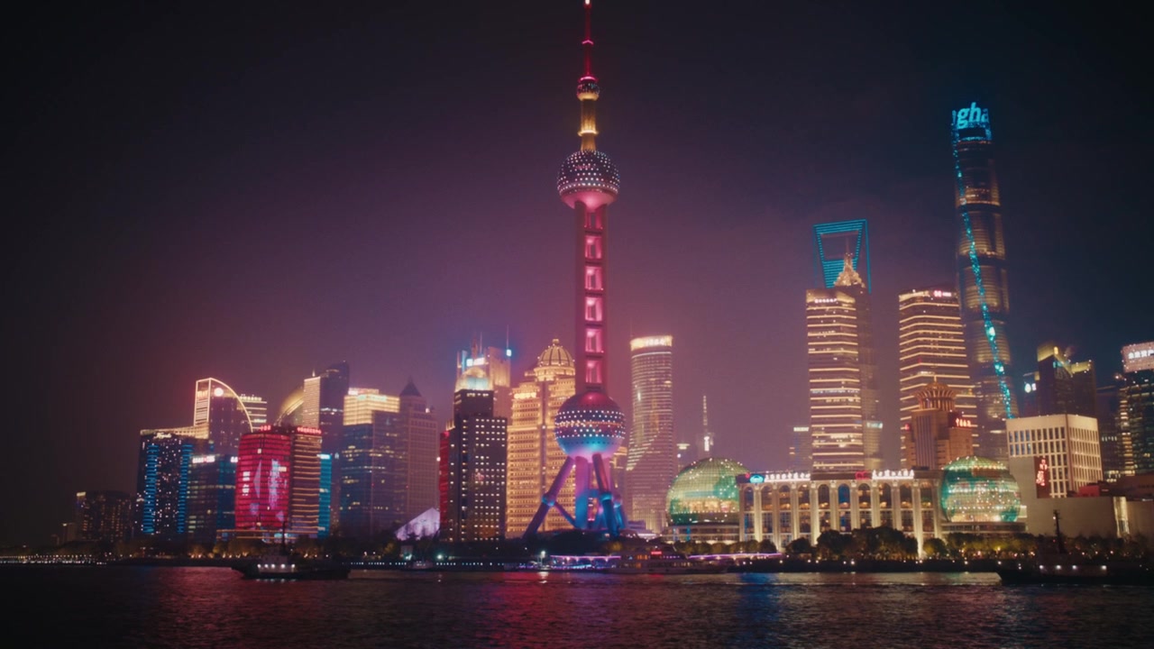 Ampia ripresa notturna dello skyline completo di Lujiazui dall'altra parte del fiume Huangpu, Shanghai. La Torre della Perla d'Oriente risplende di rosa-rosso al centro.