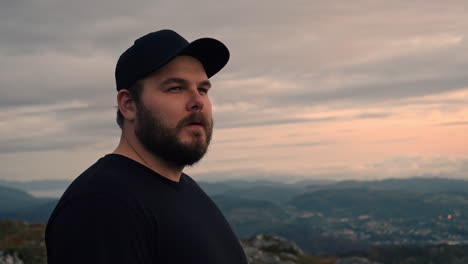 Man-lifting-his-head-and-wisely-looking-at-the-view-he-is-facing-with-mountains-in-the-background---4K-Slowmotion