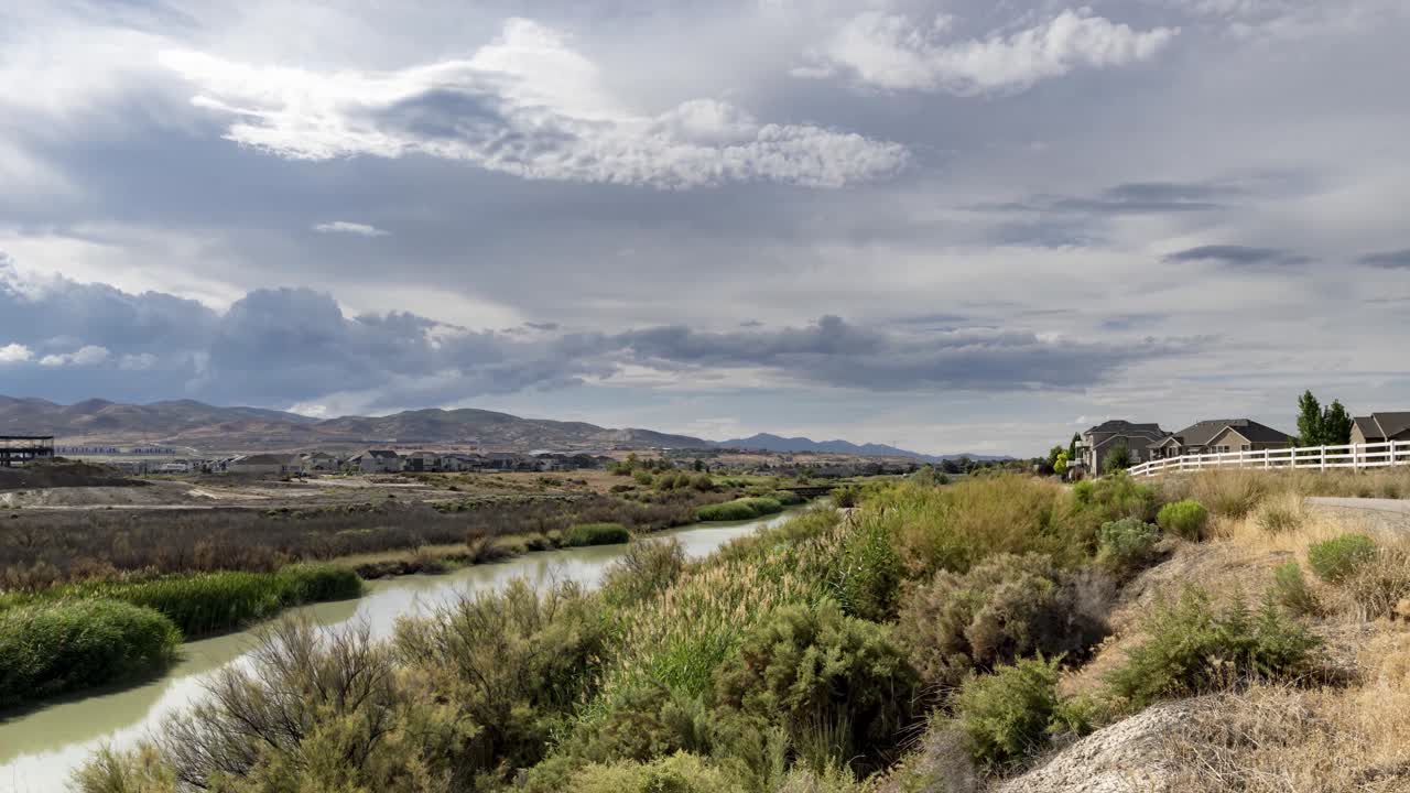 paisaje nublado sobre un río y montañas en un día de verano nublado - lapso de tiempo panorámico giratorio con el cielo reflejándose en el agua