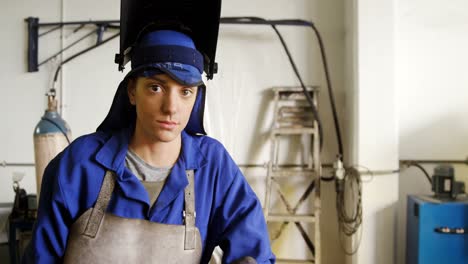 welder standing with arm crossed in workshop