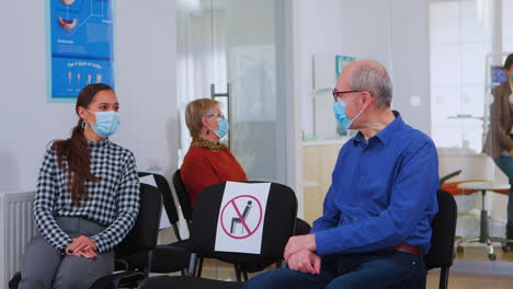 patienten mit masken sprechen, sitzen auf stühlen und halten soziale distanz.