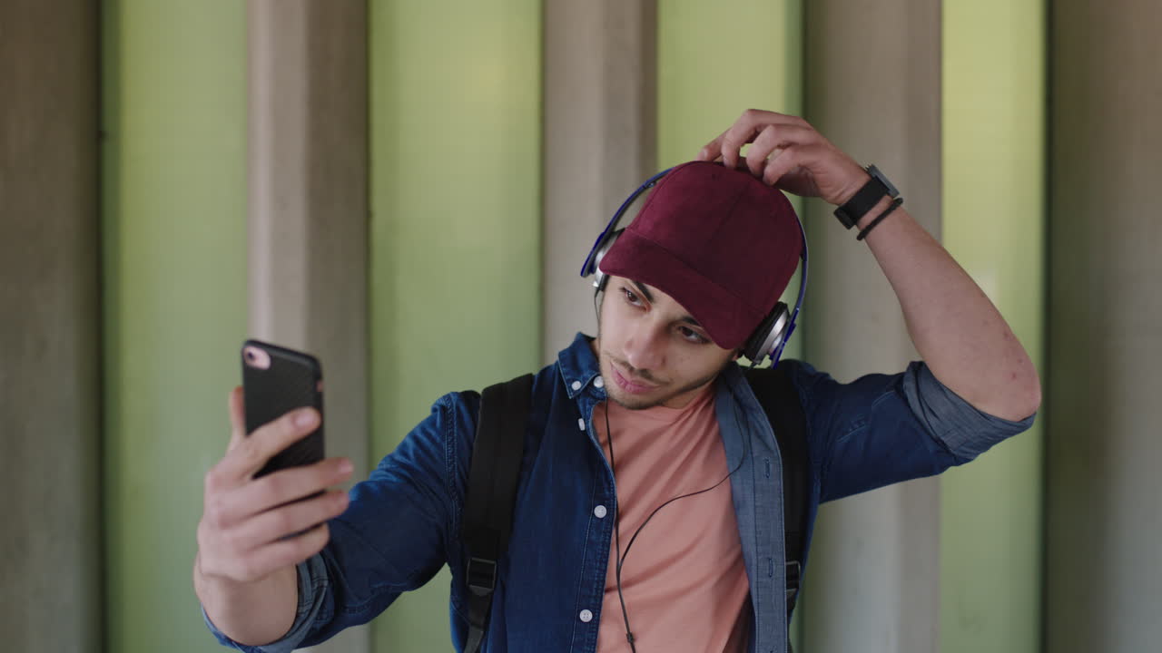 portrait of handsome young man wearing headphones taking selfie smiling happy