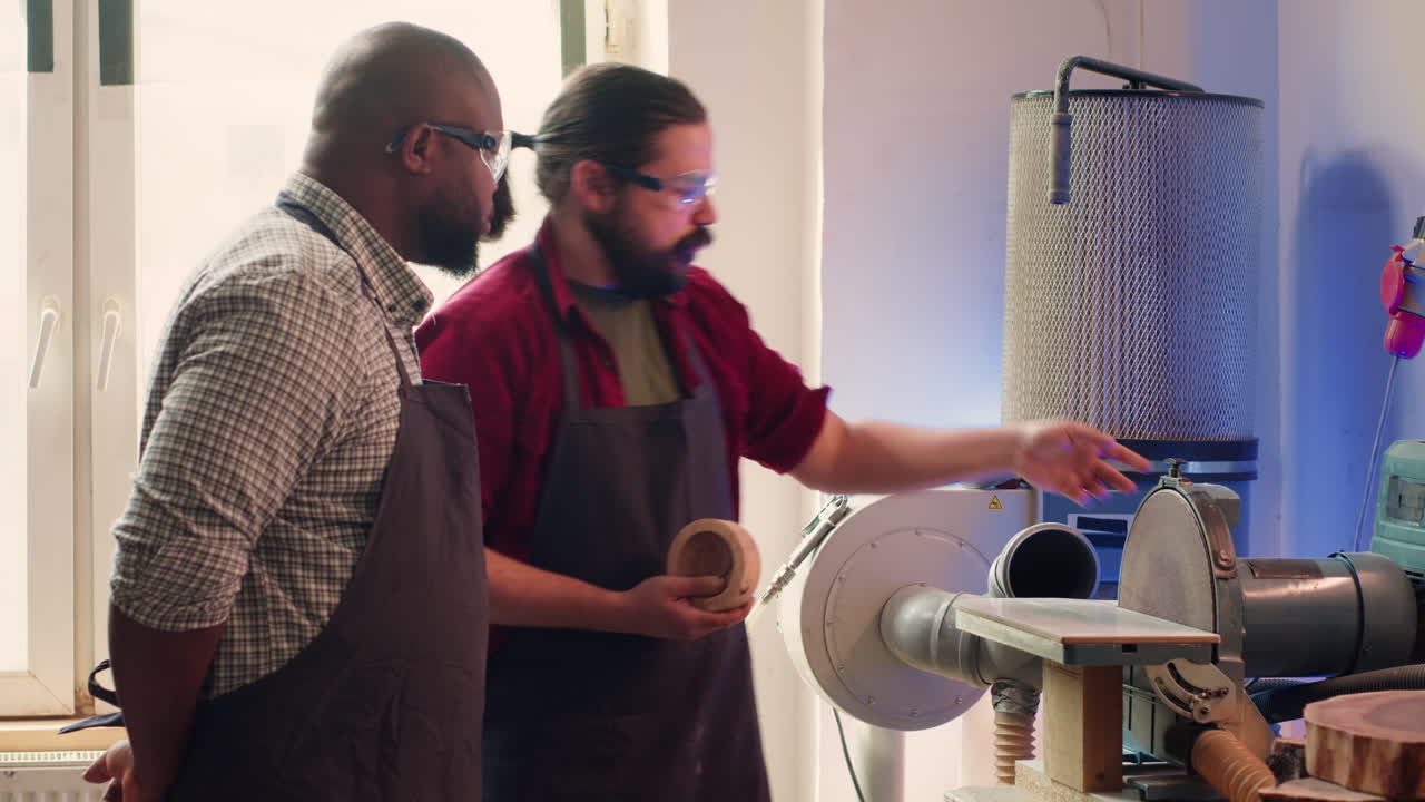 Manufacturer teaching new employee how to shape wooden bowl on disc sander