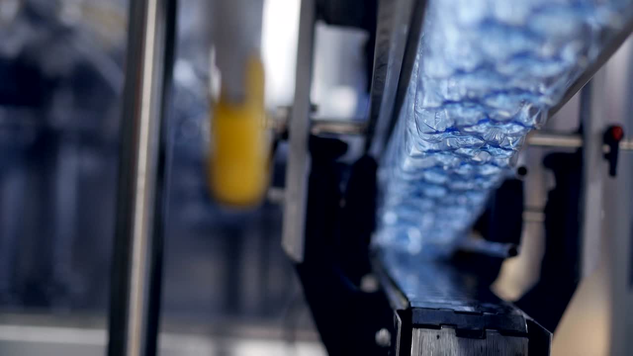 Fast moving empty bottles transferred above conveyor belt.