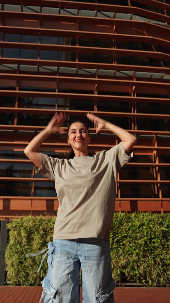 Jovem mulher dançando energicamente em frente a um edifício urbano moderno