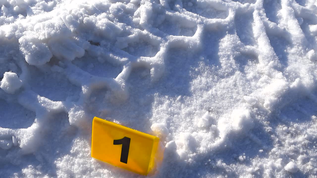 Numbered crime marker dominates frame while deep vehicle grooves recede behind across sparkling snow