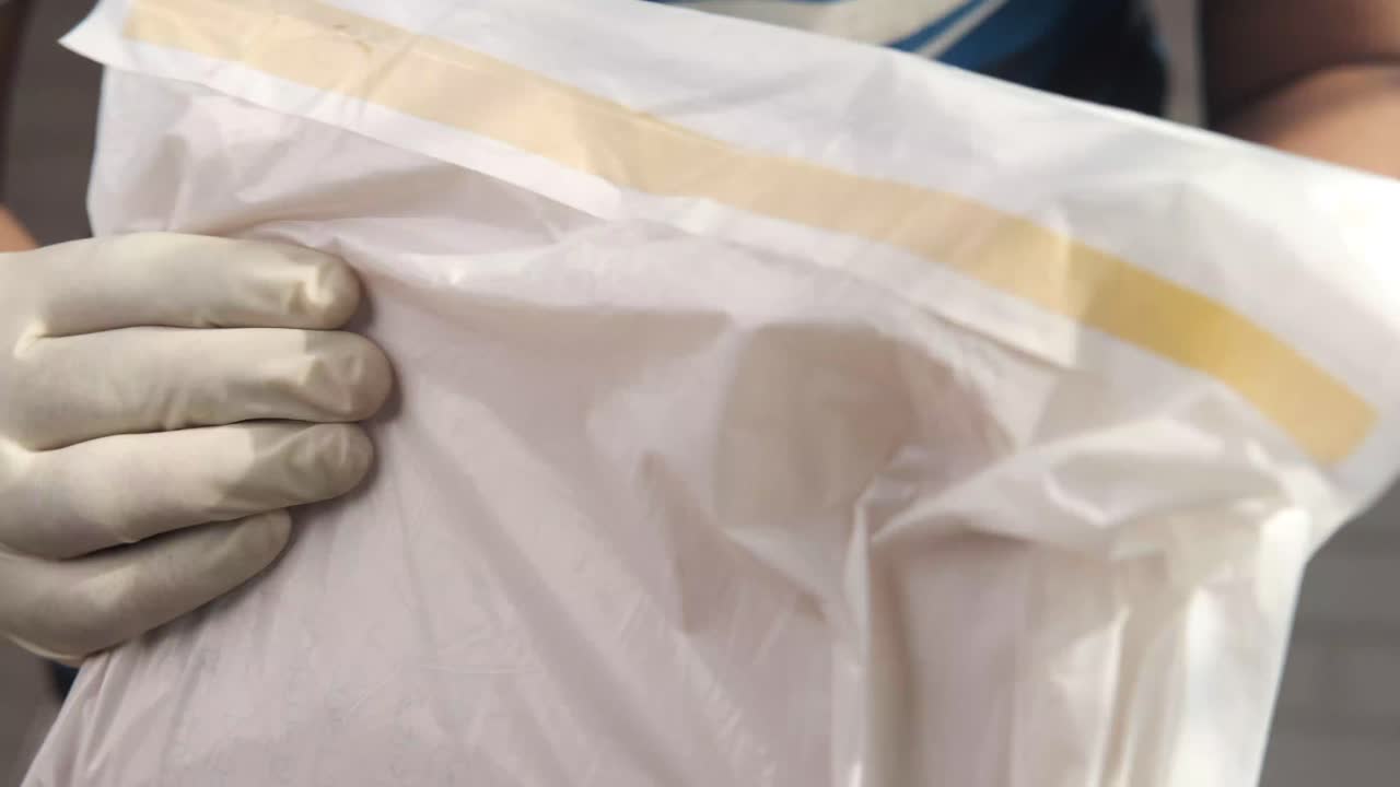 장갑 을 입은 사람 이  종이 가방 을 들고 있다