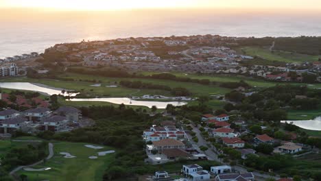 drones de camiones sobre el complejo con campo de golf junto al océano caribe al atardecer