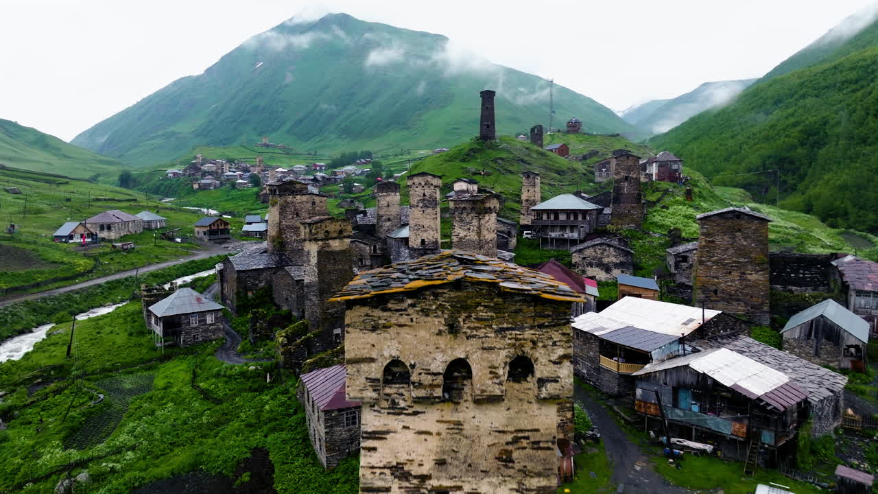 Remote Village At The Foothill Of High Mountain Peaks, Ushguli In Svaneti, Georgia. Aerial Pullback Shot
