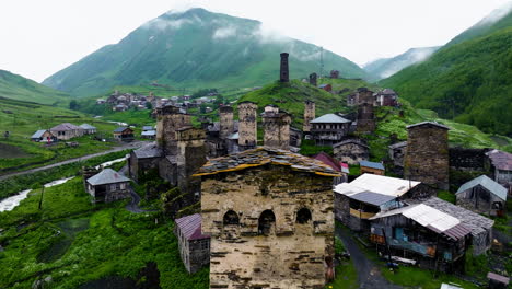 Remote Village At The Foothill Of High Mountain Peaks, Ushguli In Svaneti, Georgia. Aerial Pullback Shot