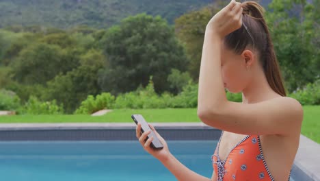 Woman-in-swimwear-using-mobile-phone-in-the-backyard-4k