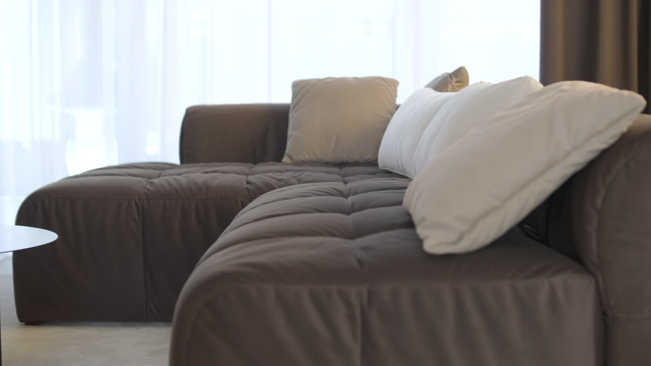 Moderne L-formet sofa med puder i en lys stue