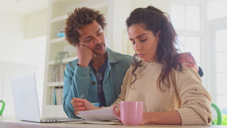 Pareja-Joven-Preocupada-Endeudada-En-Casa-Con-Una-Computadora-Portátil-Revisando-Juntas-Las-Finanzas-Internas