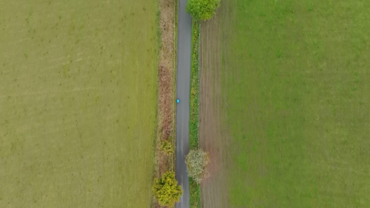 Cyclist on country road bike ride, high aerial overhead shot