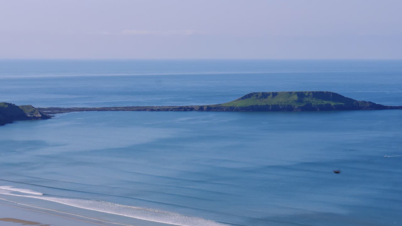 View of Worm's Head Landmark on Rhossili Bay at Low Tide on Sunny Day with Beautiful Blue Water of Atlantic Ocean in Gower Peninsula, Wales UK 4K