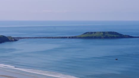 view of worm's head landmark on rhossili bay at low tide on sunny day with beautiful blue water of atlantic ocean in gower peninsula, wales uk 4k
