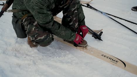 person preparing wooden skis in the snow