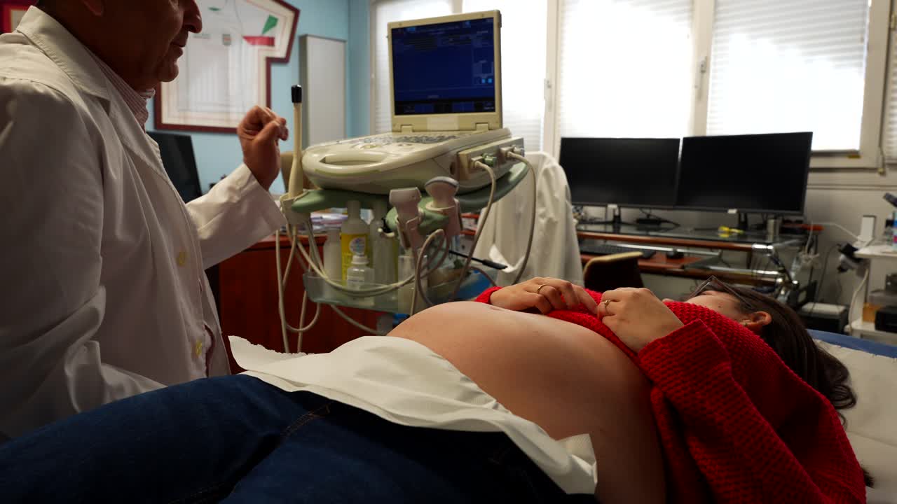 Medico che spiega alla sua paziente incinta gli aspetti dell'ecografia.