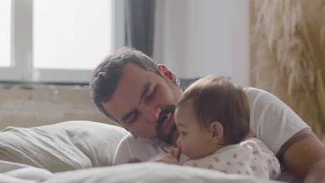 happy couple lying in bed on sunday morning and playing with their cute baby girl 3