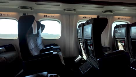 rows of empty seats inside a green car of a shinkansen bullet train, offering a glimpse of comfortable and modern rail travel in japan