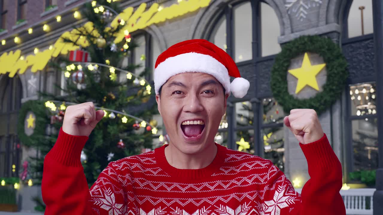 크리스마스 밤에 서서 성공을 축하하는 산타 의상을 입은 행복한 아시아인의 클로즈업