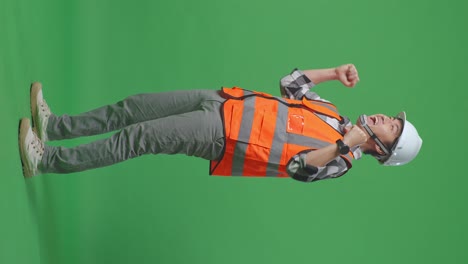 full body side view of asian male engineer with safety helmet screaming goal celebrating working in the green screen background studio