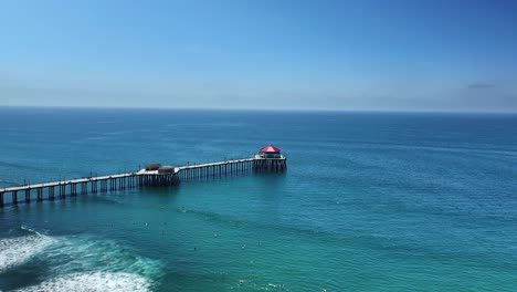flying diagonally towards the end of the huntington beach pier and over the pacific ocean