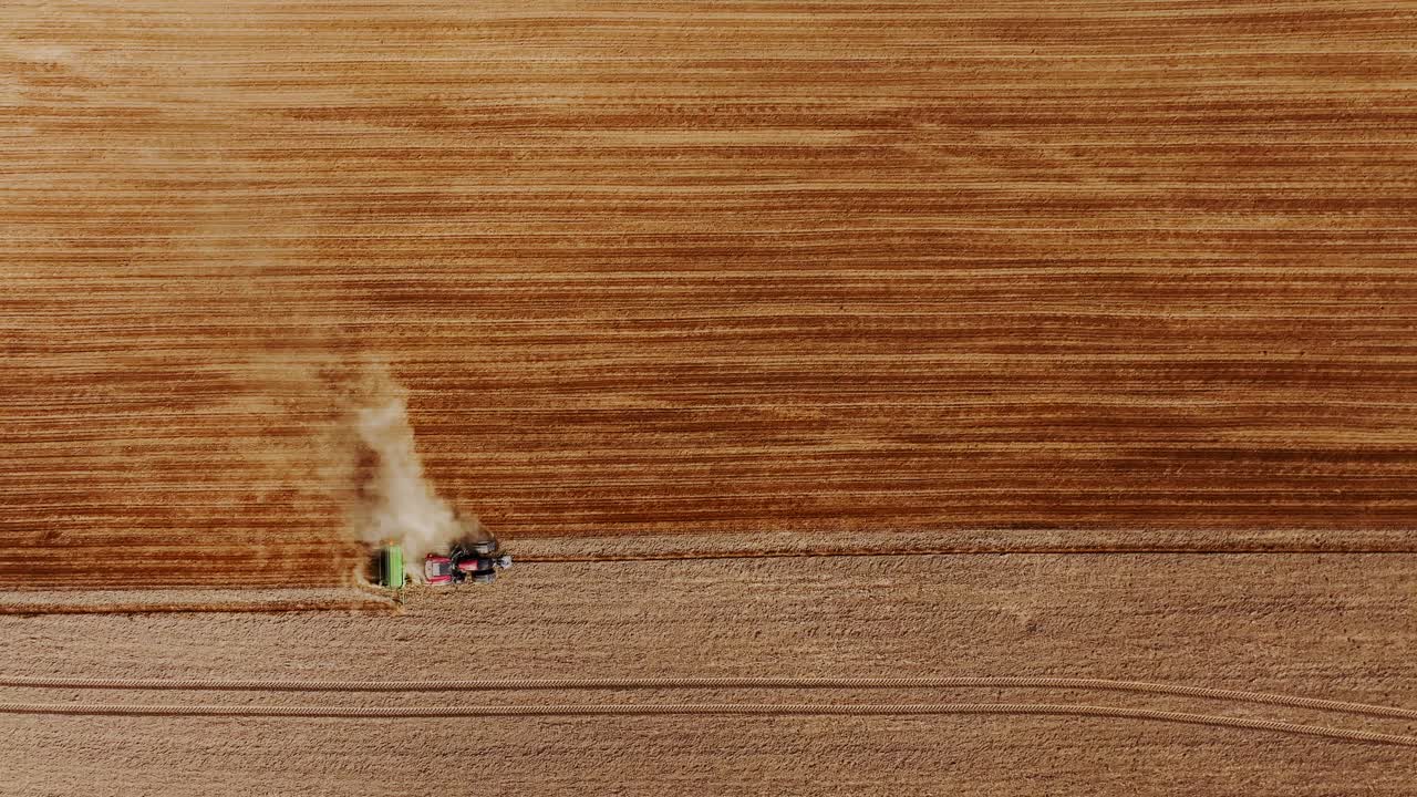 Movimento cinematico del drone dall'alto su un trattore che lavora attraverso campi agricoli dorati