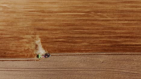 Top down cinematic drone movement over tractor working through golden farmland