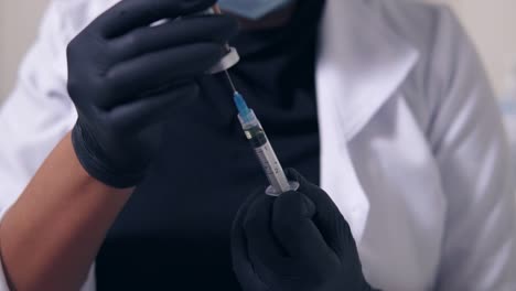 Closeup-View-Of-An-Unrecognizable-Professional-Doctor-In-Black-Gloves-And-Mask-With-Medical-Syringe-In-Hands,-Getting-Ready-For-Injection