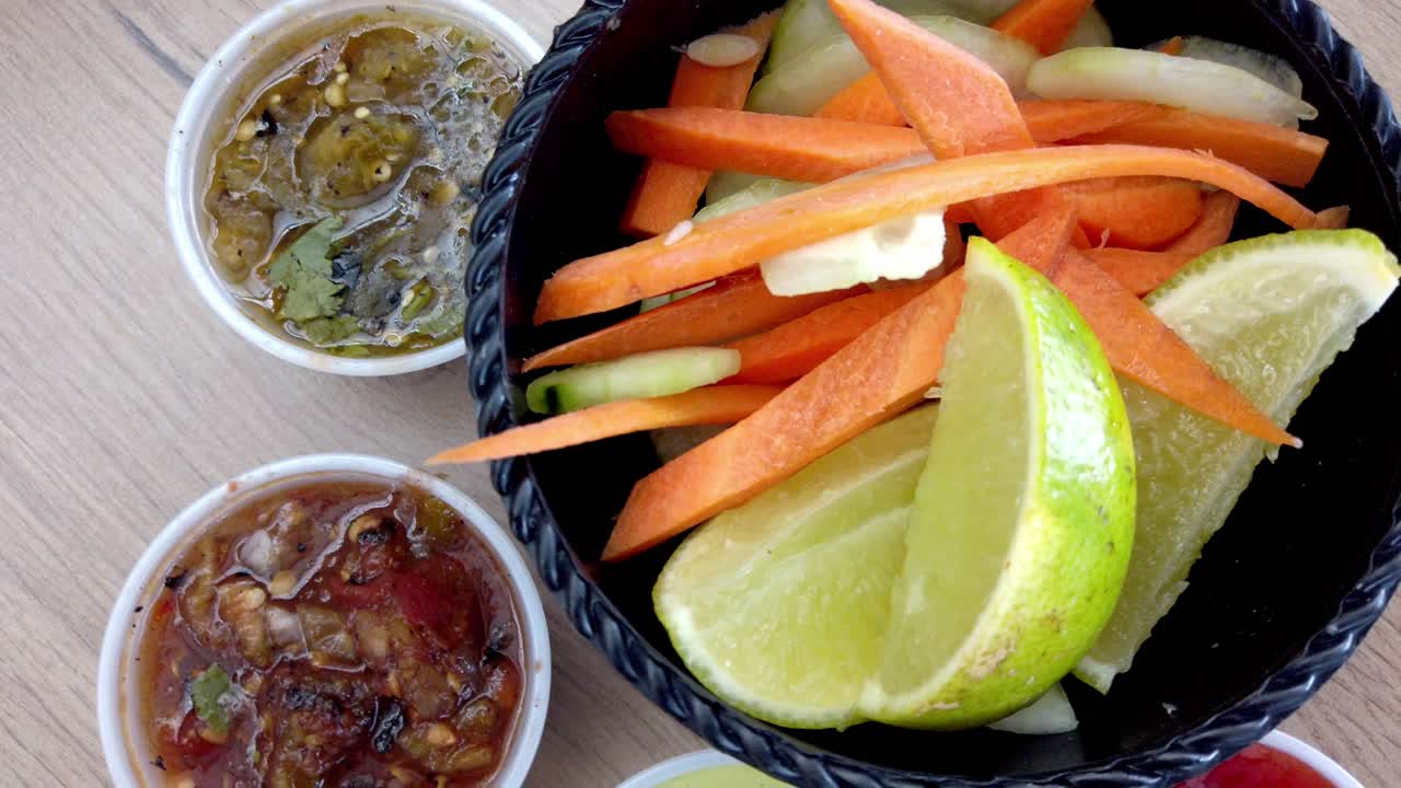 Close up of a small plastic container filled with green Mexican salsa with seeds and cilantro