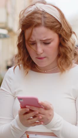 Woman using smartphone typing browsing loses bad news fortune loss fail fraud on urban city sunny