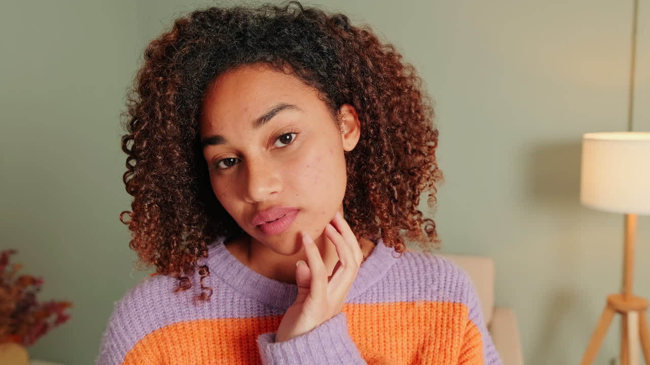 Thoughtful Young Woman with Curly Hair Looks at Camera and Smiles