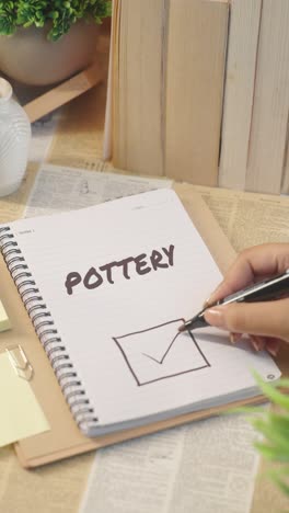 vertical video of ticking off pottery work from checklist