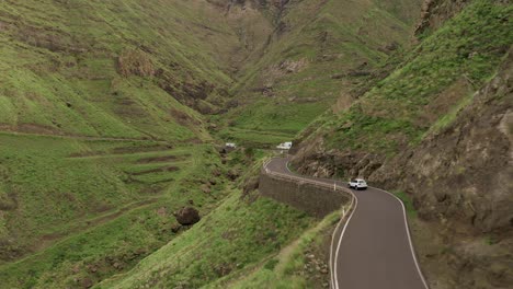 Drohnenaufnahme-Eines-Autos,-Das-Auf-Einer-Straße-In-Einer-Grünen-Schlucht-Fährt